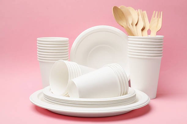 Set of disposable tableware on pink background